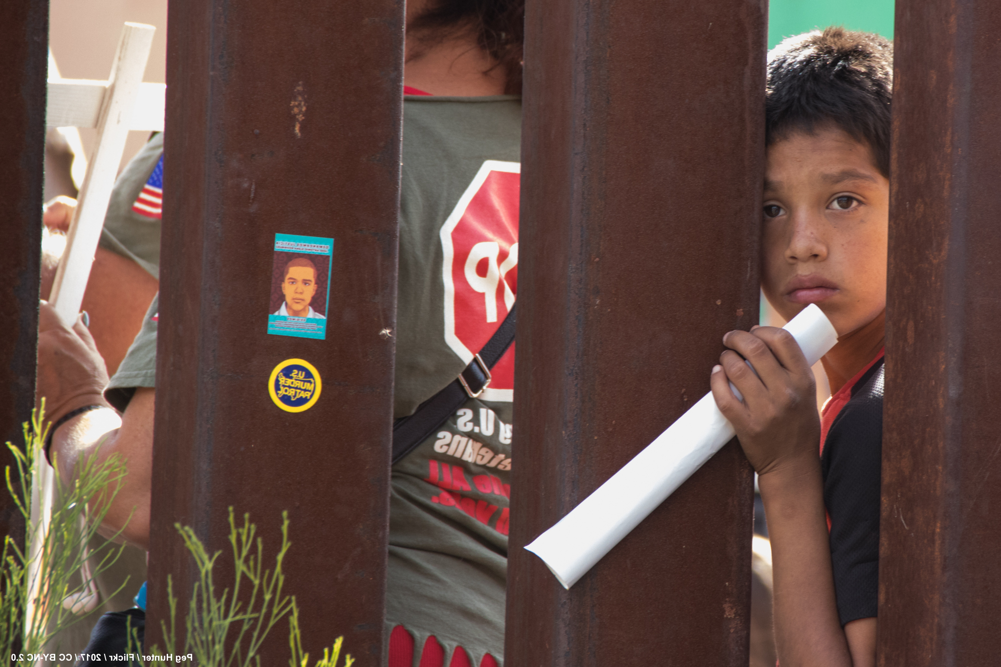 Photo of migrant kid looking over the border