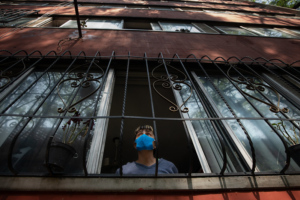 person looking out of a barred window